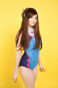 Portrait of woman standing against yellow background