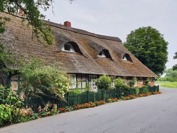 Ancient stilt house with thatched roof by road