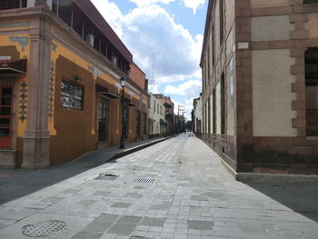 Empty alley amidst buildings in city against sky