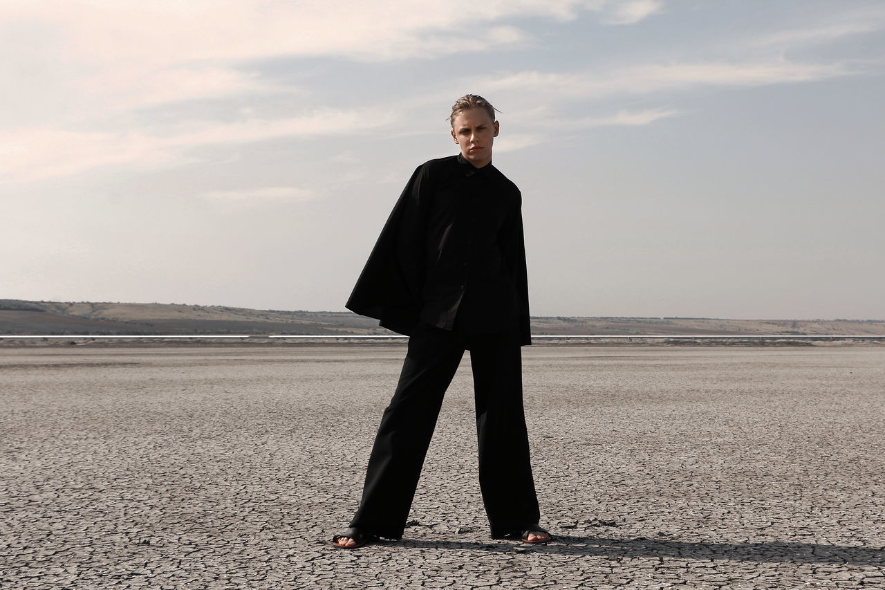 sky, one person, full length, standing, land, real people, scenics - nature, water, young adult, tranquility, nature, lifestyles, beach, tranquil scene, day, non-urban scene, front view, salt flat