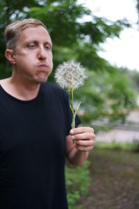 Young man holding dandelion flower