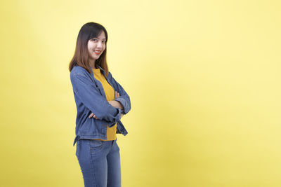 Side view of a smiling young woman against yellow background