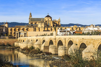 Arch bridge over river against buildings