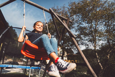Low angle view of boy swinging at playground