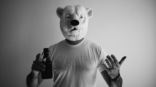 Portrait of man wearing mask standing against wall