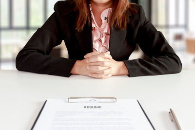 Midsection of woman sitting at table