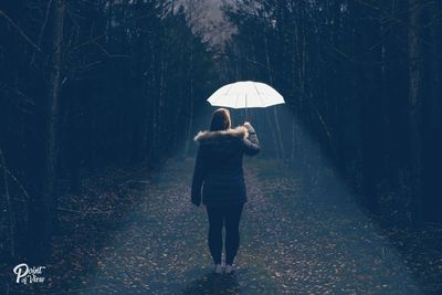 Rear view of woman standing with umbrella