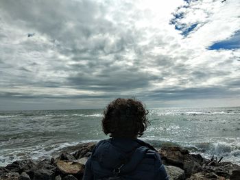 Rear view of boy looking at sea against sky