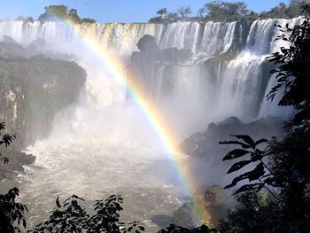 Scenic view of waterfall against rainbow in sky