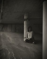 Portrait of woman sitting under klarabergsviadukten bridge against column