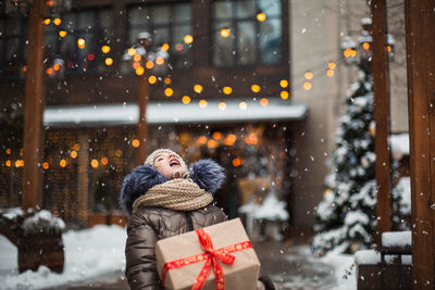 Cute girl holding gift box outdoors