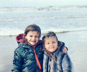 Portrait of siblings standing against sea