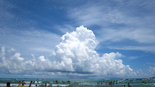 Panoramic view of people on beach against blue sky