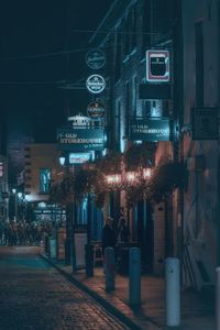 Illuminated street amidst buildings in city at night