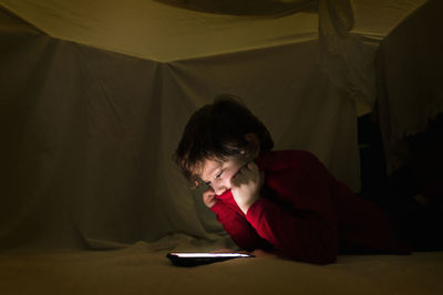 Boy using mobile phone while lying down on bed at home