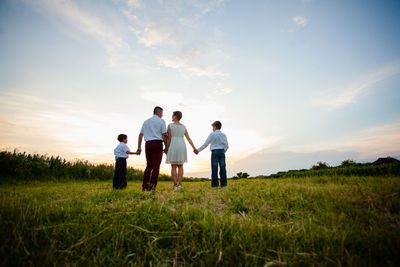 People standing on field against sky during sunset