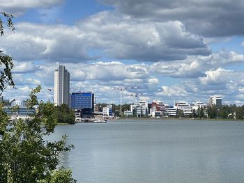 Modern buildings by river against sky