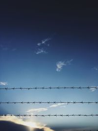 Low angle view of birds on cable against sky