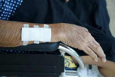 Close-up of senior woman with injured hand on wheelchair