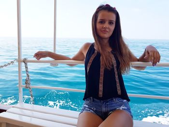 Portrait of young woman in swimming pool against sea