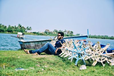 People sitting on land by sea against sky