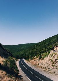 Road by mountain against clear blue sky