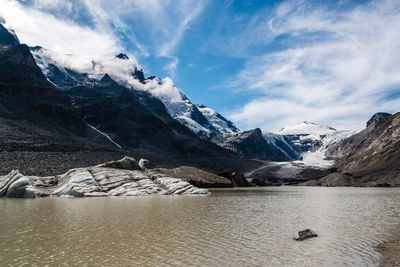 Scenic view of lake by mountains against sky during winter