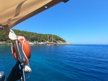 Boat sailing in sea against clear blue sky