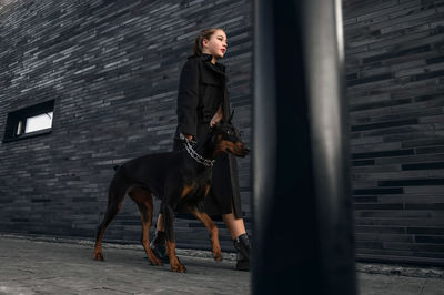 Teen girl walking down the street with her doberman. great view.  security and confidence concept