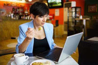 Young woman using laptop at cafe