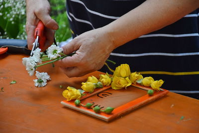 Midsection of florist cutting flowers on table in shop