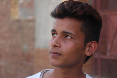 Close-up of young man looking away while standing outdoors