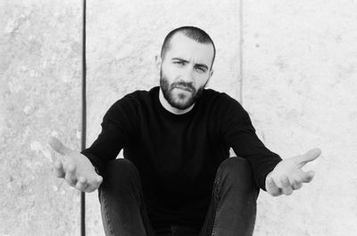 Portrait of man gesturing while sitting against window