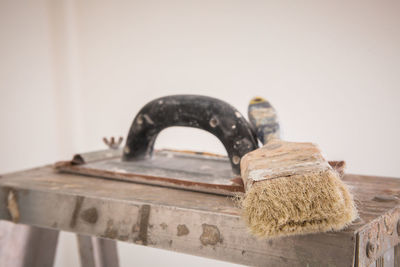 Close up of hand tool and paintbrush on ladder at home