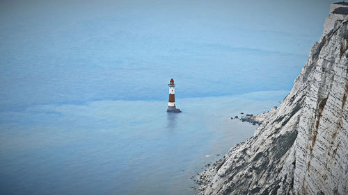 Old lighthouse in the middle of the sea next to white cliffs 