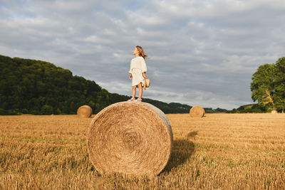 Rear view of woman standing on hay