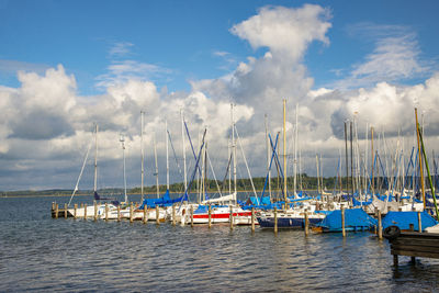 Sailboats moored in sea against sky
