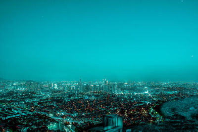 High angle view of illuminated cityscape against clear blue sky