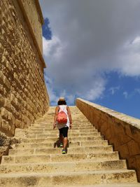 Low angle view of woman walking on staircase against sky