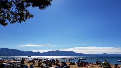 Group of people on beach against blue sky