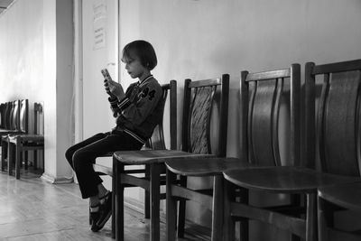 Boy sitting on chair in a corridor