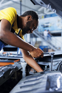 Side view of man repairing car
