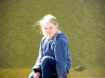 Full length of teenage girl sitting by lake