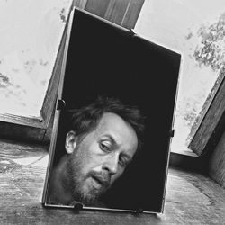 Portrait of man looking through window at home