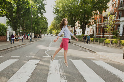 Woman dancing over road against sky