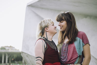 Smiling young couple looking at each other against wall