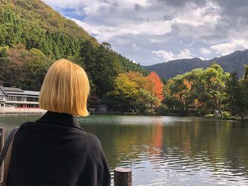 Rear view of woman looking at lake against sky