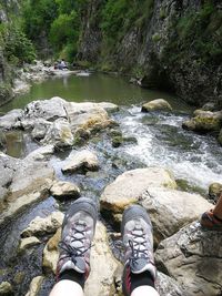 Low section of man standing on rock by river