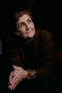 Senior woman looking away against black background