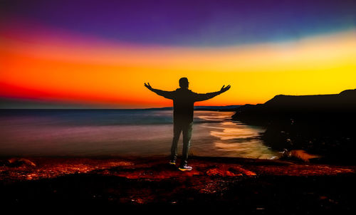 Silhouette man standing by sea against sky during sunset